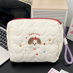 Detail of white quilted makeup bag with dog embroidery and red puppy land text