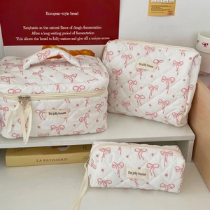 Detailed set of three quilted makeup bags with pink bow print and zipper closure