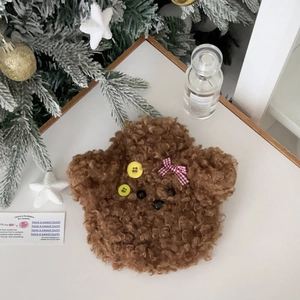 Detail of teddy bear plush hot water bottle cover with red bow in a cozy Christmas setting