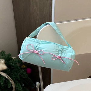 Close-up of a light blue quilted pencil case with pink bows and a round handle