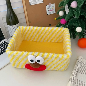 Close-up of yellow striped plush storage bin with cartoon clown face on desktop