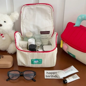 Cute house-themed corduroy makeup bag with red trim and travel toiletries