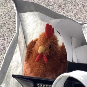 Jouet de coq en peluche marron à texture douce et crête rouge dans un sac tissé gris