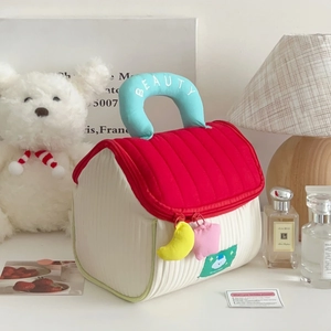 Detail of cute house-shaped makeup bag with blue handle and colorful plush charms