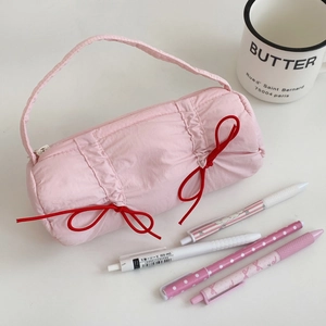 Detailed view of pink barrel pencil case featuring elegant red ribbon bow decorations