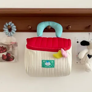 Quilted fabric cosmetic bag with red lid, blue beauty handle, and plush pendants