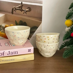Off-white ceramic bowl set with colorful star and floral patterns in a home setting