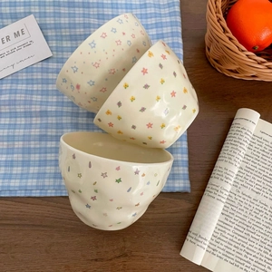 Detailed view of hand-painted ceramic bowls with colorful star patterns and wavy edges