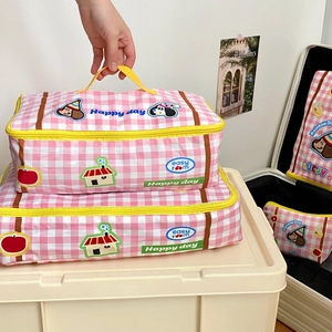 Close-up of pink checkered travel organizers with yellow zippers and cute illustrations