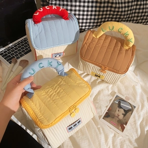 Detailed view of three quilted house-shaped cosmetic bags with lucky embroidered handles
