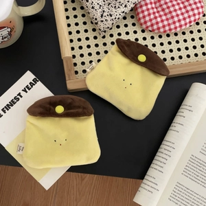 Macro shot of two plush caramel pudding coin pouches on a rustic woven tray setup