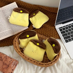 Detailed view of five plush pudding-shaped coin purses on a woven basket with a cozy home vibe