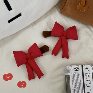 Detail of red bow hair clips with brown plush bases on a cozy aesthetic background