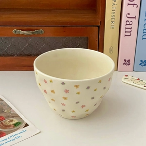 Close-up of cream ceramic bowl with colorful floral pattern in a cozy home setting