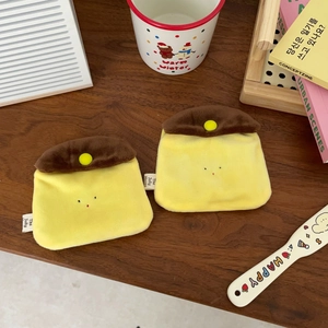 Flat lay of cute caramel pudding plush coin purses on a cozy wooden desk with books