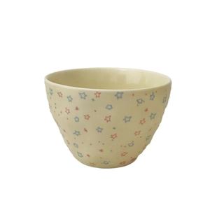 Ceramic salad bowl with red and blue star patterns on off-white surface, minimalist design