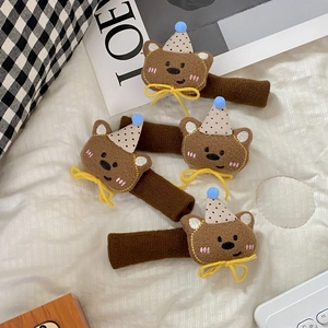 Detailed view of four cute plush bear handle covers with polka dot hats on a soft mat