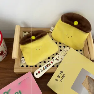 Detail of cute pudding plush coin purses in a wooden tray with a brand woven label