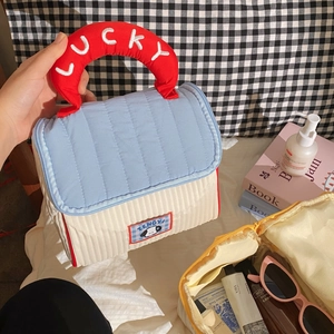Quilted cosmetic bag with lucky red handle and house design for travel organization