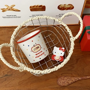 Macro shot of a cartoon apple ceramic mug and decorative kitty clip in a metal mesh basket