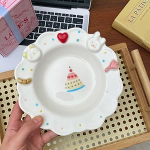 Detail of white ceramic plate with 3D embossed animals and pink layered cake design