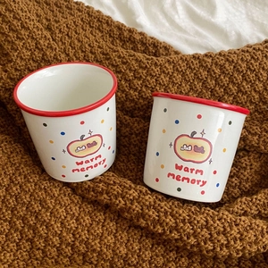 Detail of white ceramic apple mug with red rim and dots on brown knit background