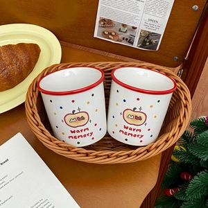 Cozy breakfast setting with apple-themed ceramic mugs and croissants in a woven basket