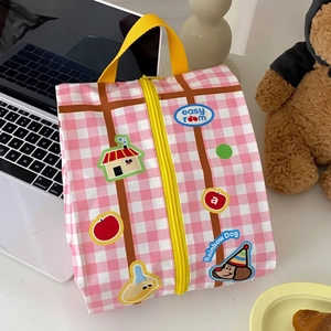 Close-up of pink checkered travel organizer bag with cute cartoon patches and yellow zipper