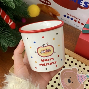 Close-up of ceramic apple mug with red rim and warm memory print in festive setting