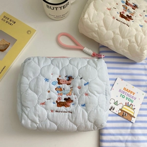 Detail of blue quilted cosmetic bag with cute dachshund embroidery and pink carry strap