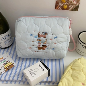 Close-up of cute sausage dog embroidery on a light blue quilted cosmetic bag with pink zipper