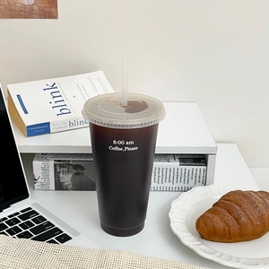 Wiederverwendbarer Kaffeebecher mit Strohhalm und 8:00 am Aufdruck auf einem Schreibtisch