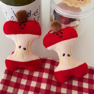 Macro shot of two apple core plush pendants on a red and white checkered cloth