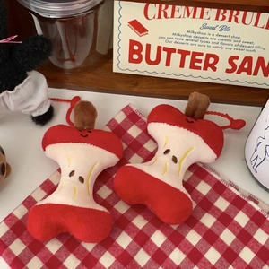 Detail of apple core plush pendants with cute embroidery on a red checkered napkin