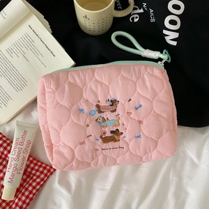 Detail of pink quilted makeup bag with dachshund embroidery and mint green zipper handle