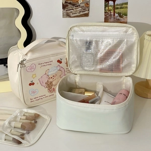 Internal compartments of a cream makeup bag featuring cartoon prints and mesh zip pocket