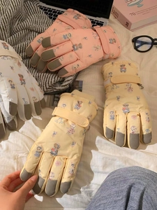 Close-up of pink, white, and yellow bear ski gloves featuring anti-slip palm texture