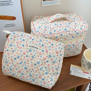 Detailed view of floral corduroy cosmetic bag set on wooden table with warm home decor