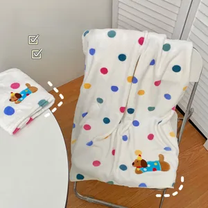 Close-up of soft coral fleece bath towel featuring colorful polka dots and dog embroidery