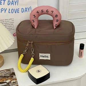Detail of a brown cosmetic bag featuring pink handle and yellow spring zipper puller