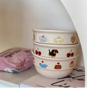 Close-up of three stacked ceramic bowls with cream finish and cute cartoon animal illustrations