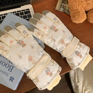 Detail of waterproof teddy bear ski gloves with touchscreen tips on a cozy wooden desk