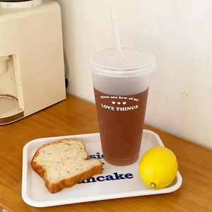 Translucent plastic coffee tumbler with straw featuring white decorative text and a lid