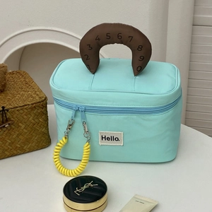 Close-up of mint green cosmetic bag with a yellow spiral zipper and brown handle