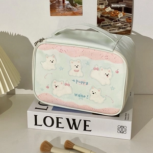 Detail of light green cosmetic bag featuring cute white puppy illustrations and top handle
