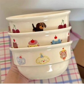 Close-up of stacked cream ceramic bowls with cute hand-painted puppy and elephant patterns