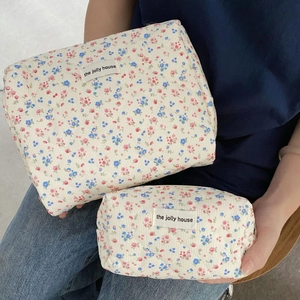 Close-up of quilted floral corduroy makeup bags in cream with brand label detail