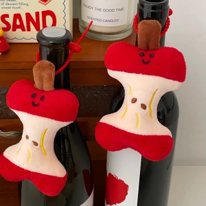 Cute apple core plush keychains with embroidered smile faces on a decorative bottle