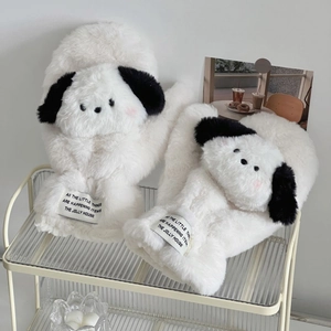 Detail of plush cream puppy slippers featuring fuzzy texture and decorative woven labels