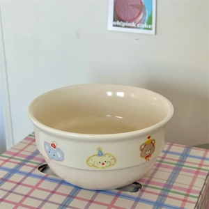 Detail of cream ceramic bowl featuring cute cartoon animals in a cozy home setting